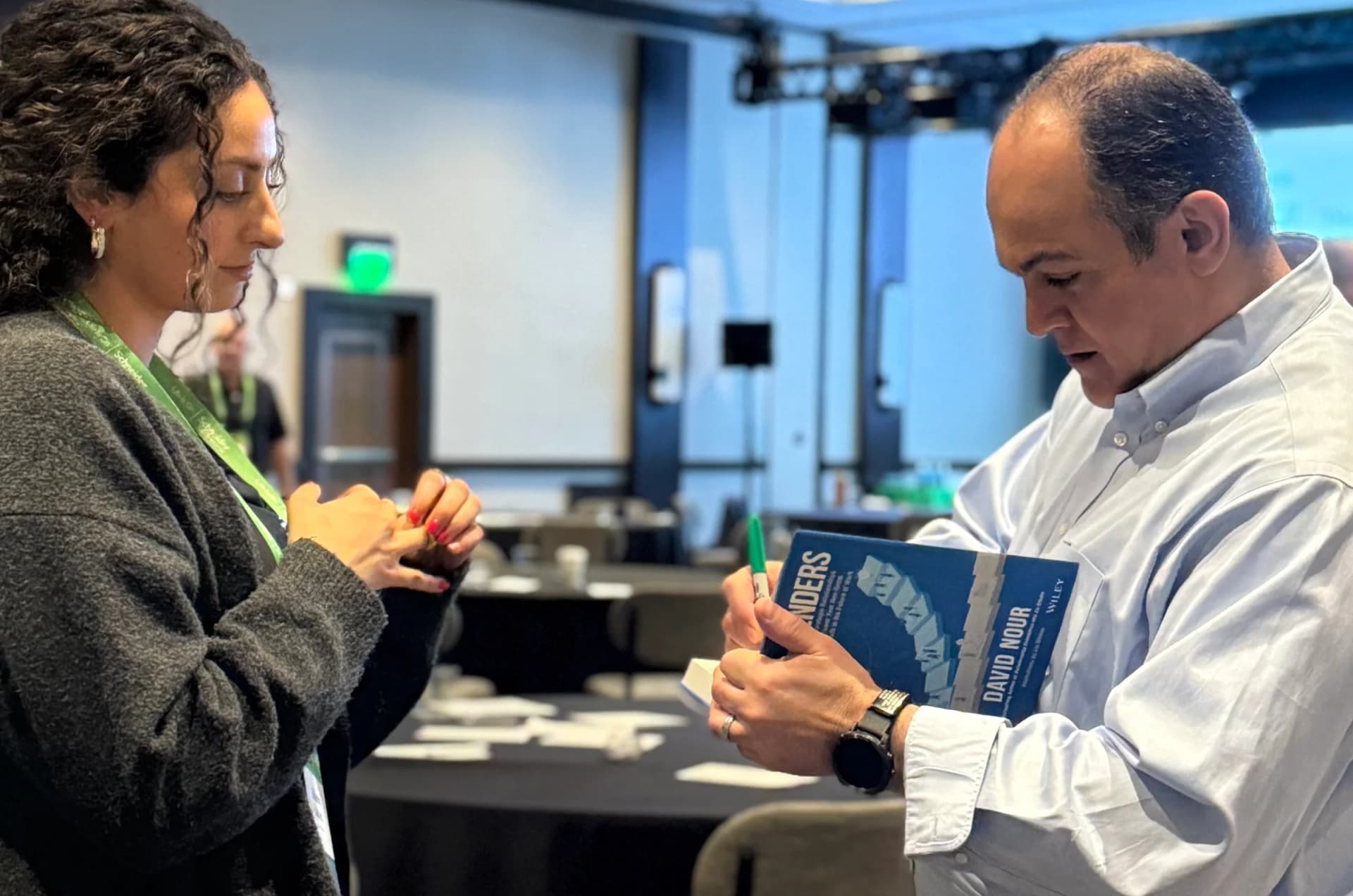 David Nour signing books and speaking with a reader